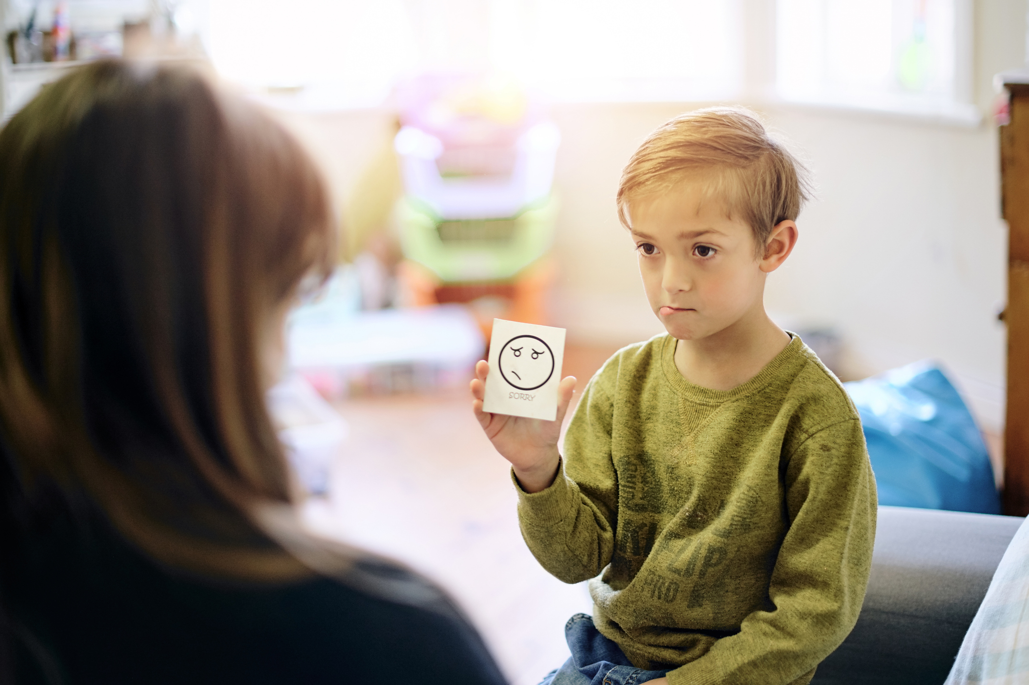 Petit garçon montrant une carte d'émotion en séance