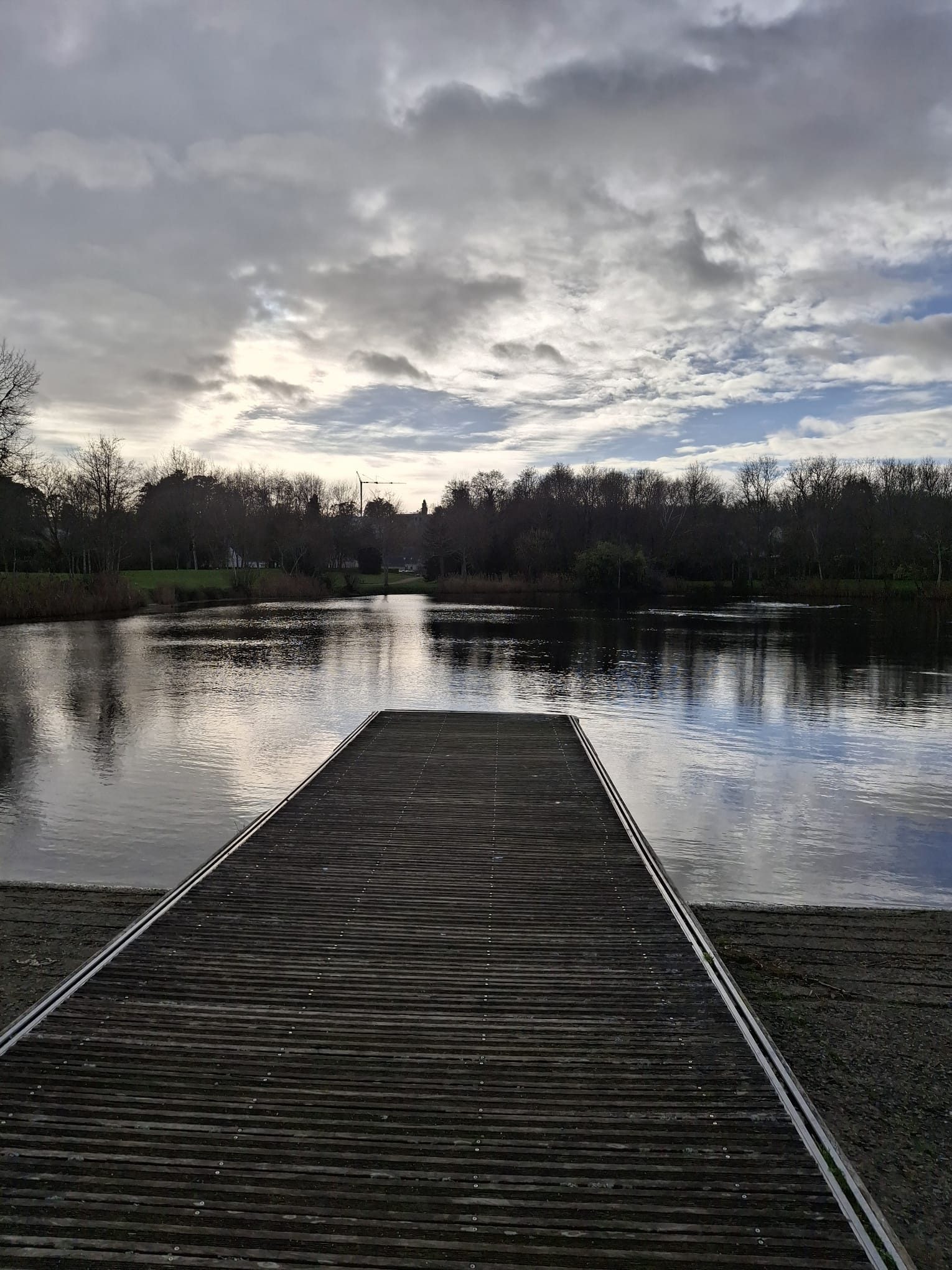 Ponton sur un lac calme sous un ciel où la lumière revient